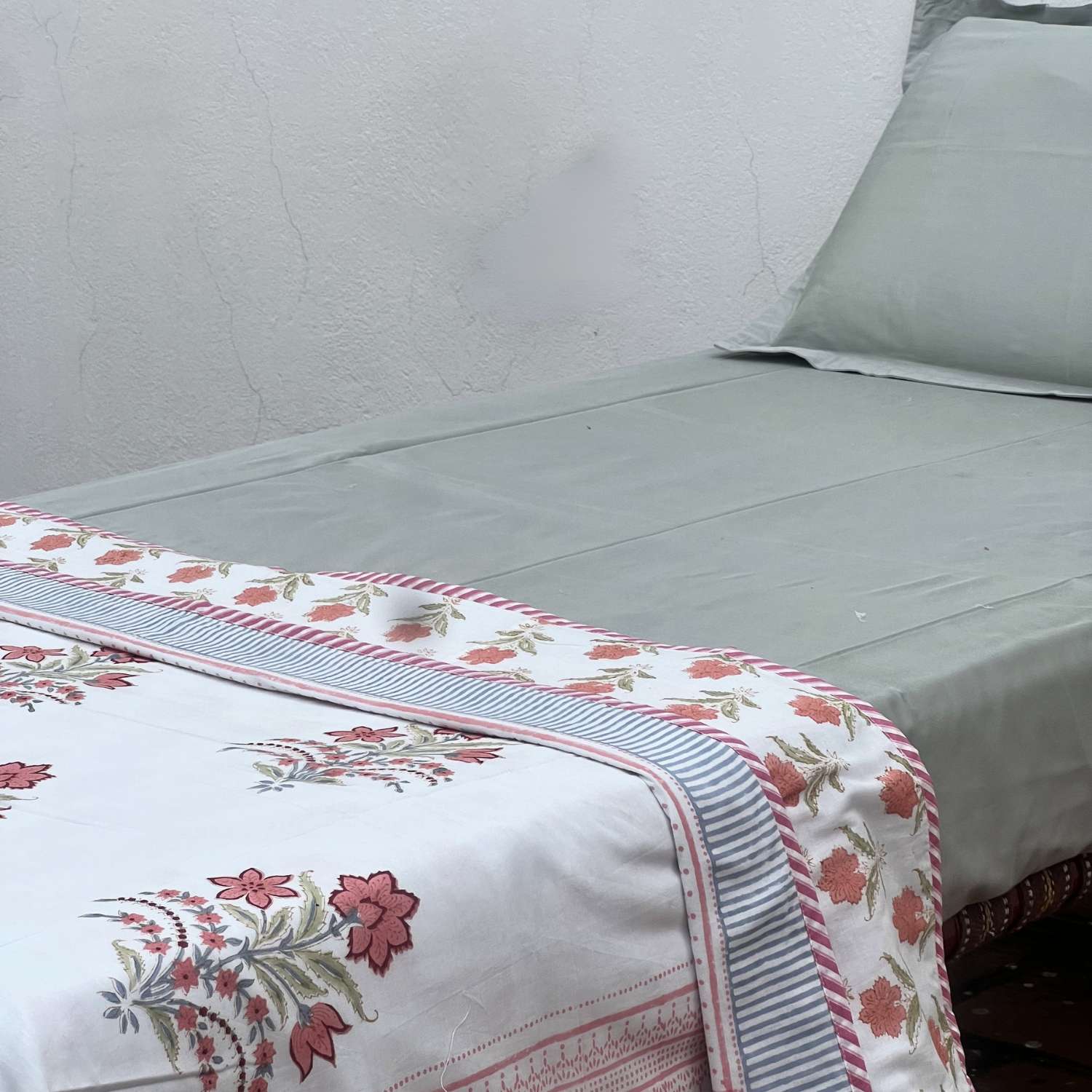 Floral embroidered blanket on a bed with a white background