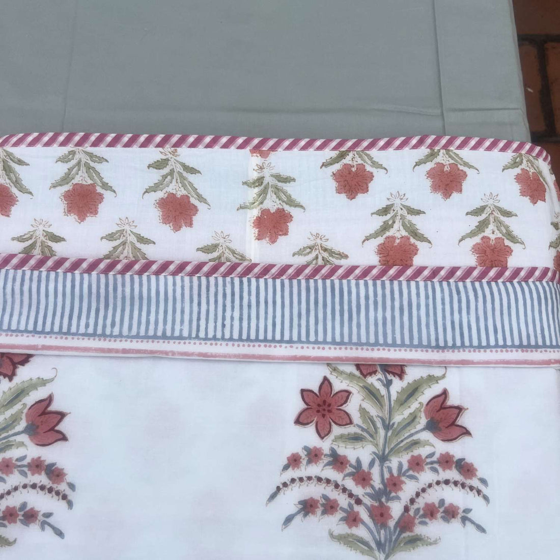 Floral embroidered blanket on a bed with a white background
