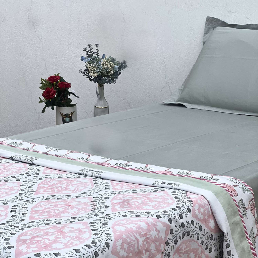 Bed with floral quilt and gray pillow against a neutral wall