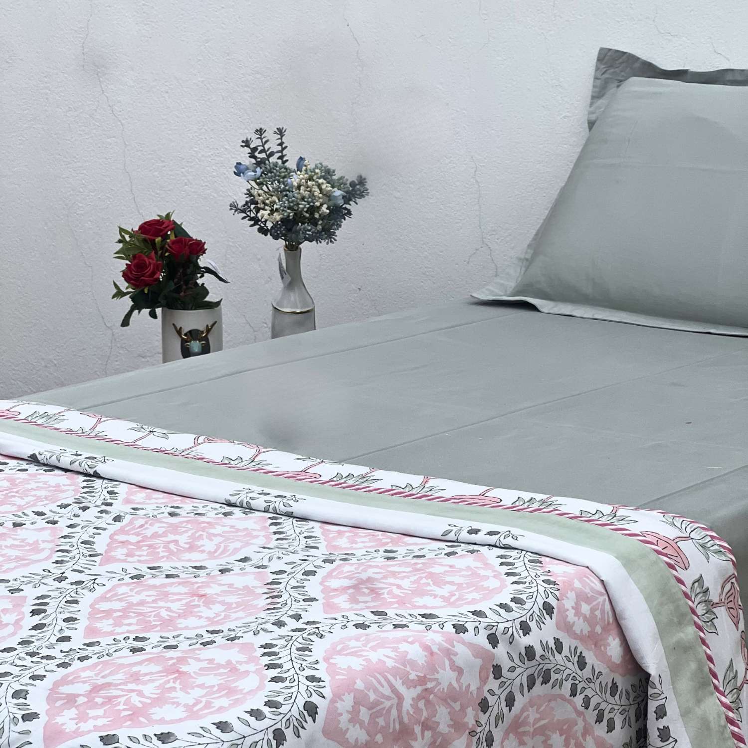Bed with floral quilt and gray pillow against a neutral wall