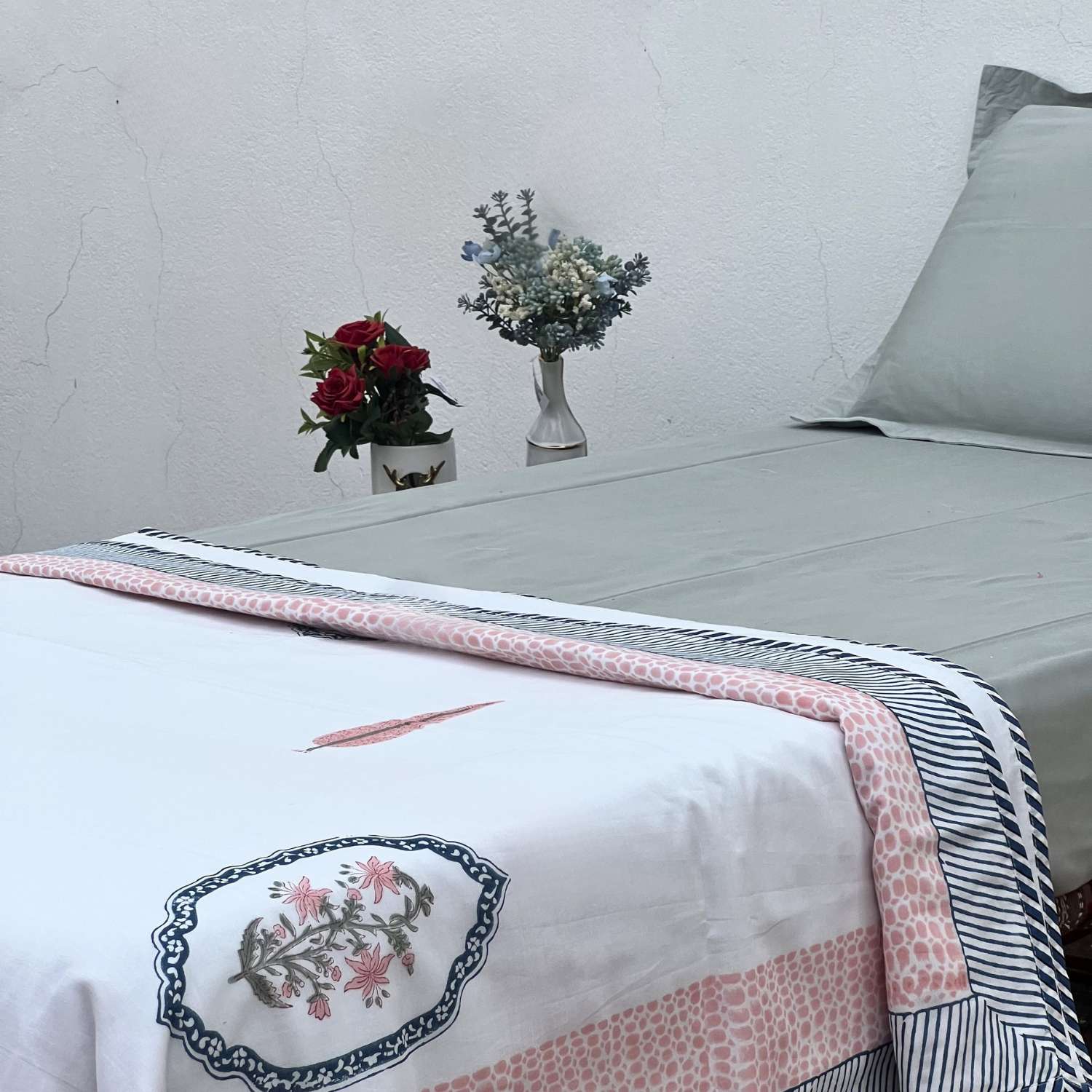 Bed with floral patterns and vases on a white wall